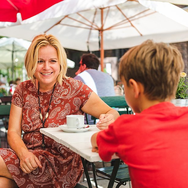 Eine Mutter sitzt mit ihrem Sohn auf der Terrasse des Café Paresüd im Natur Park Südgelände